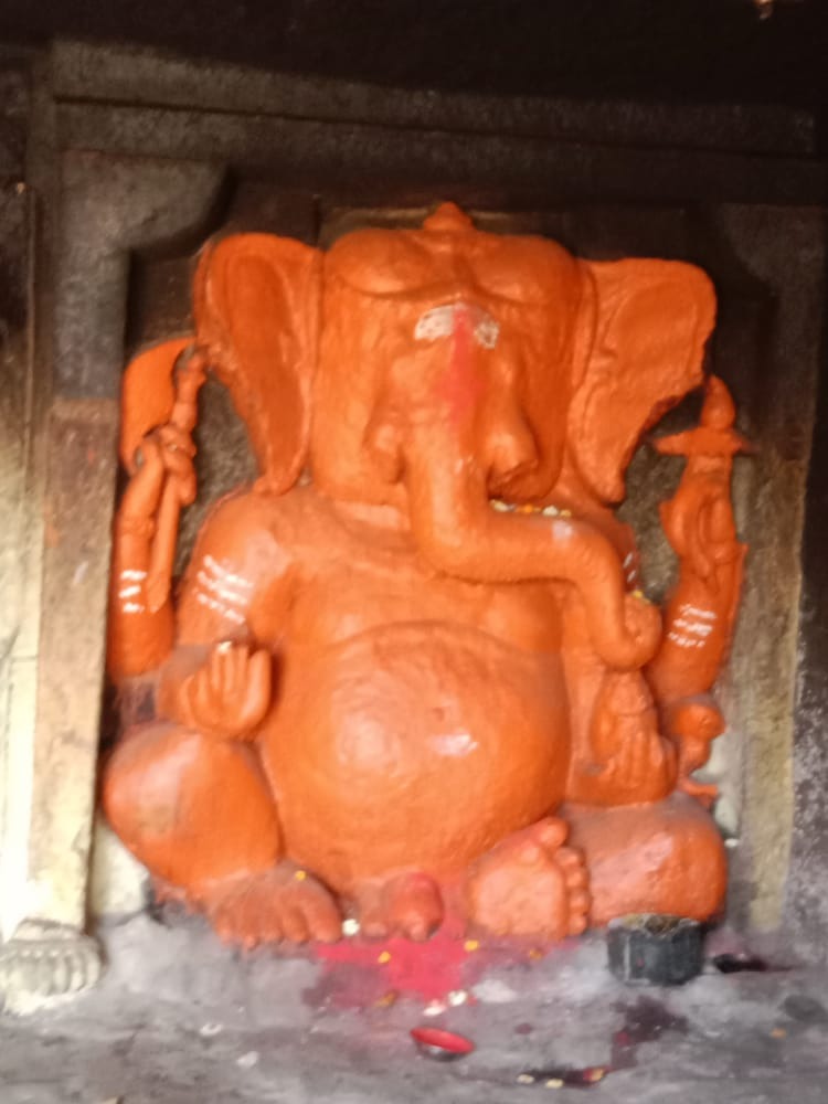 Orange Ganpati idol carved into stone cave wall